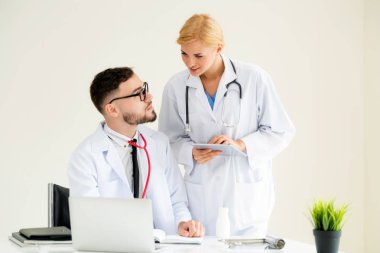 Doktor hastane ofis dizüstü bilgisayar masanın üzerinde başka bir doktor hasta sağlık hakkında tartışma ile çalışma.