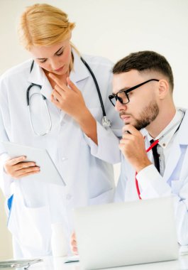 Doktor hastane ofis dizüstü bilgisayar masanın üzerinde başka bir doktor hasta sağlık hakkında tartışma ile çalışma.