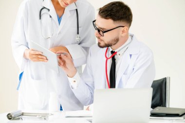 Doktor hastane ofis dizüstü bilgisayar masanın üzerinde başka bir doktor hasta sağlık hakkında tartışma ile çalışma.
