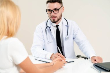 Erkek doktor hastane ofiste bayan hasta konuşuyor. Sağlık ve tıbbi hizmet.