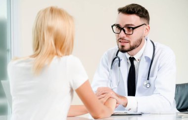 Erkek doktor hastane ofiste bayan hasta hasta ellerini tutarak yatıştırır. Sağlık ve tıbbi hizmet.