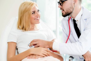 Erkek doktor konuşuyor ve Bayan hasta hastane ofisinde inceleyerek. Sağlık ve tıbbi hizmet.