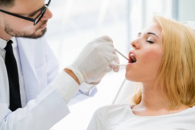 Genç yakışıklı dişçi diş diş kliniği, dişçi sandalyeye mutlu kadın hasta oturan incelenmesi. Diş Hekimliği bakım kavramı.