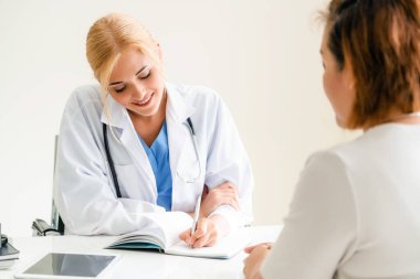 Kadın doktor konuşuyor ve Bayan hasta hastane ofisinde inceleyerek. Sağlık ve tıbbi hizmet.