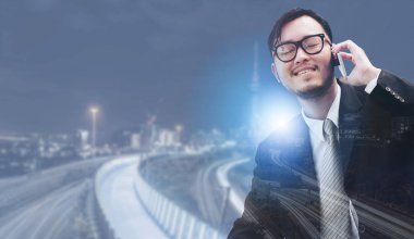 Genç işadamı istimal hareket eden telefon ile modern şehir binaları arka plan.