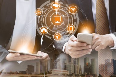 Cep telefonu ile modern şehir binaları arka plan kullanarak genç iş adamları. Gelecekteki telekomünikasyon teknolojisi ve internet şeyler (çok) kavramının.
