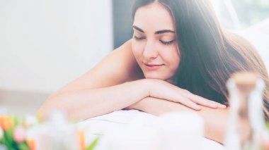 Rahat kadın lüks Spa'da aromaterapi masaj spa yatak kaplıca tedavisi aromatik yağ, mum ve bitki bodur gibi ayarla bulanık önalan ile yatan. Sağlık ve şifa kavramı.