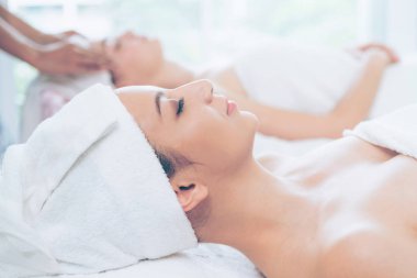 Spa yatağında uzanan rahat genç bir kadın lüks bir spa merkezinde yüz bakımı ve masaj için hazırlandı. Sağlık, stres atma ve gençleştirme kavramı.