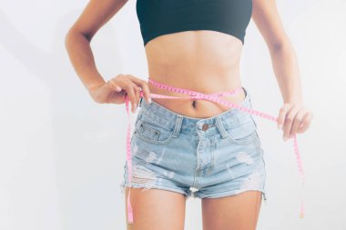 Young slim woman measures her waist by measuring tape after diet against white backgrounds. Concept of weight loss success. clipart