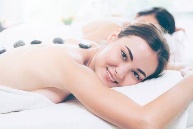 Kadın kaplıca salonunda profesyonel güzellik terapisti tarafından sıcak taş masajı görüyor. Lüks sağlık, sırt stresi ve gençleştirme kavramı..