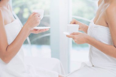 İki kadın lüks günlük kaplıcada konuşma yaparken çay veya bitkisel içecekler içme. Sağlık, eğlence ve sağlık kavramı.