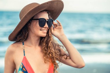 Tatil seyahat etmek tatil için yaz aylarında tropikal plaj keyfi yerinde mayo giyen mutlu genç kadın.
