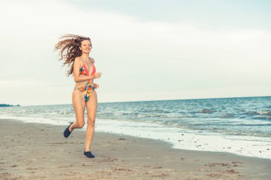 Çekici kadın runner yaz aylarında tropikal Kum Plajı üzerinde çalışır. Sağlıklı yaşam tarzı ve koşma spor kavramı.