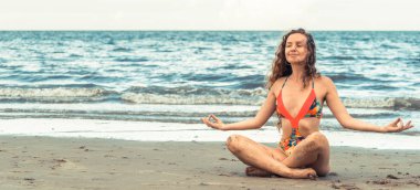 Genç kadın pratik yoga poz sahilde yaz. Sağlıklı yaşam tarzı ve meditasyon.