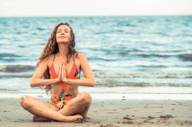 Genç kadın pratik yoga poz sahilde yaz. Sağlıklı yaşam tarzı ve meditasyon.