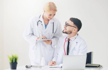 Doktor hastane ofis dizüstü bilgisayar masanın üzerinde başka bir doktor hasta sağlık hakkında tartışma ile çalışma.