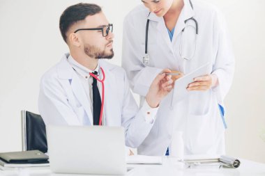 Doktor hastane ofis dizüstü bilgisayar masanın üzerinde başka bir doktor hasta sağlık hakkında tartışma ile çalışma.