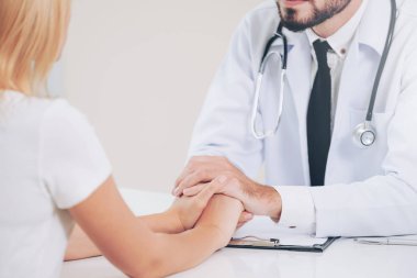 Erkek doktor hastane ofiste bayan hasta hasta ellerini tutarak yatıştırır. Sağlık ve tıbbi hizmet.