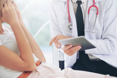 Erkek doktor konuşuyor ve Bayan hasta hastane ofisinde inceleyerek. Sağlık ve tıbbi hizmet.