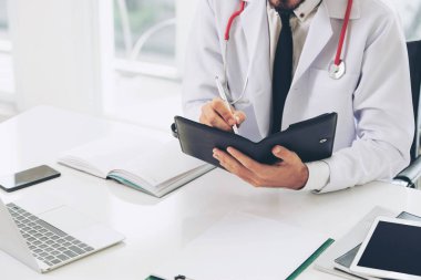 Doktor ofisinde hastanede bir kitap üzerine not yazarken okuma. Tıbbi ve sağlık kavramı.