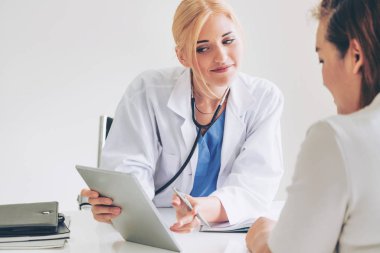 Kadın doktor konuşuyor ve Bayan hasta hastane ofisinde inceleyerek. Sağlık ve tıbbi hizmet.