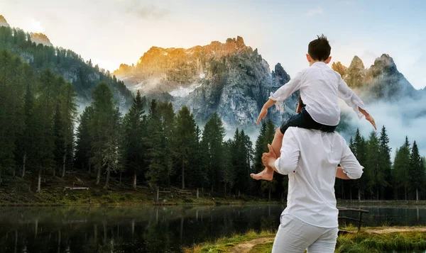 Happy father carrying his son on shoulders is on vacation and escape to nature.
