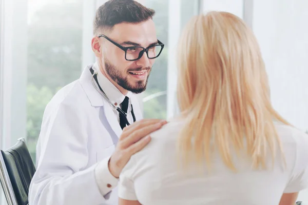 Male doctor is talking with female patient in hospital office. Healthcare and medical service.