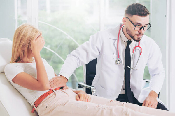 Male doctor is talking and examining female patient in hospital office. Healthcare and medical service.