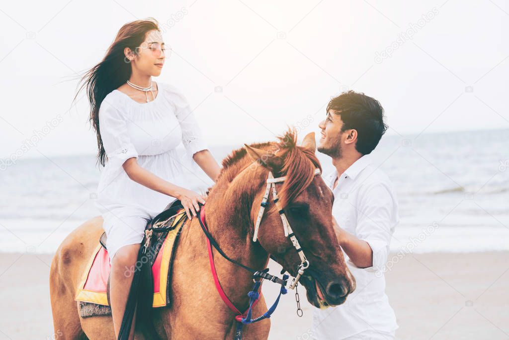 Young couple goes honeymoon horse riding on the beach in summer vacation.