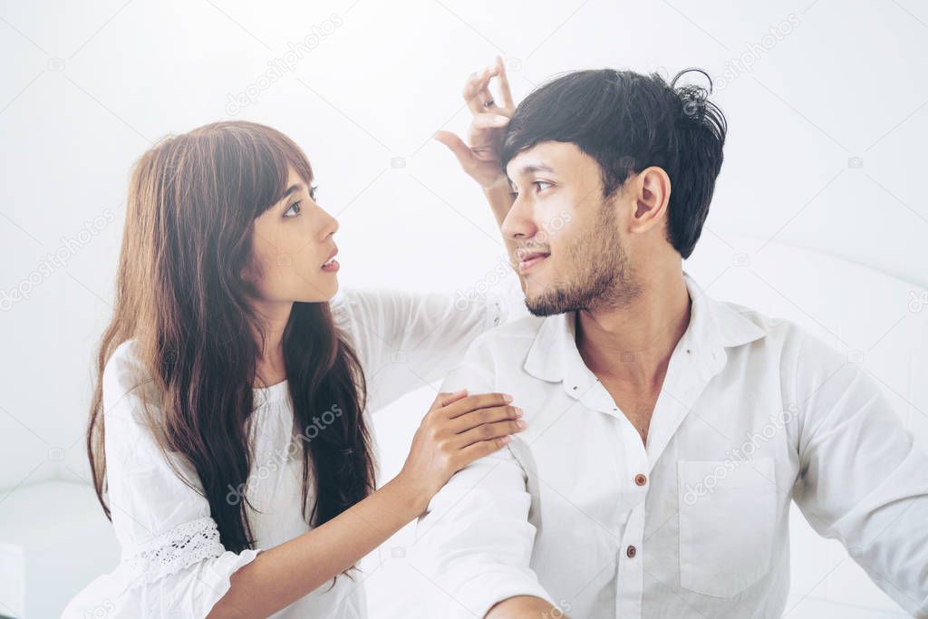 Happy young couple relaxing in home bedroom after waking up in the morning.