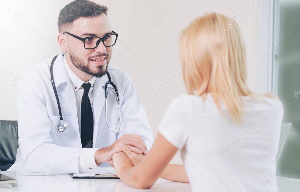 Male doctor soothes a female patient in hospital office while holding the patients hands. Healthcare and medical service.