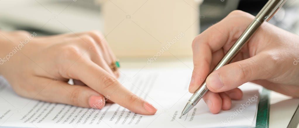 Businesswoman signs agreement contract with another businesswoman at the office. Close up shot at the woman's hand. Concept of business partnership and legal activities of lawyer.