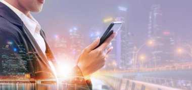 Cep telefonu ile modern şehir binaları arka plan kullanarak genç iş kadını. Gelecekteki telekomünikasyon teknolojisi ve internet şeyler (çok) kavramının.