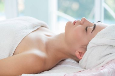Spa yatağında uzanan rahat genç bir kadın lüks bir spa merkezinde yüz bakımı ve masaj için hazırlandı. Sağlık, stres atma ve gençleştirme kavramı.