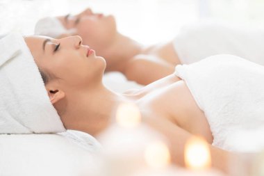 Spa yatağında uzanan rahat genç bir kadın lüks bir spa merkezinde yüz bakımı ve masaj için hazırlandı. Sağlık, stres atma ve gençleştirme kavramı.