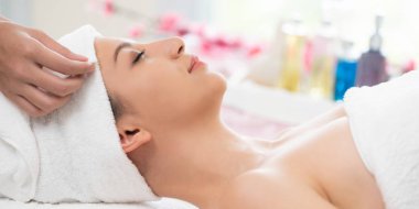 Spa yatağında uzanan rahat genç bir kadın lüks bir spa merkezinde yüz bakımı ve masaj için hazırlandı. Sağlık, stres atma ve gençleştirme kavramı.
