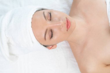 Spa yatağında uzanan rahat genç bir kadın lüks bir spa merkezinde yüz bakımı ve masaj için hazırlandı. Sağlık, stres atma ve gençleştirme kavramı.