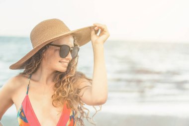 Tatil seyahat etmek tatil için yaz aylarında tropikal plaj keyfi yerinde mayo giyen mutlu genç kadın.