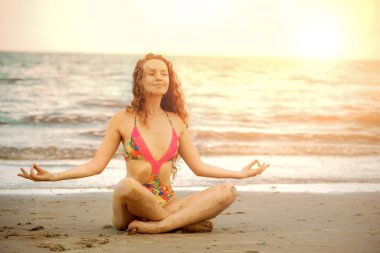 Genç kadın pratik yoga poz sahilde yaz. Sağlıklı yaşam tarzı ve meditasyon.