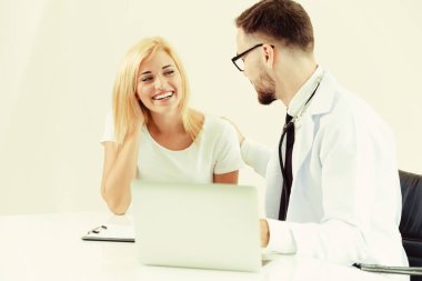 Erkek doktor hastane ofiste bayan hasta masada dizüstü bilgisayarda hastalar sağlık verilere bakarken konuştuğu. Sağlık ve tıbbi hizmet.