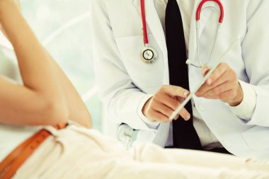 Erkek doktor konuşuyor ve Bayan hasta hastane ofisinde inceleyerek. Sağlık ve tıbbi hizmet.
