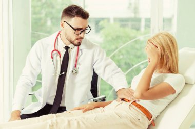 Erkek doktor konuşuyor ve Bayan hasta hastane ofisinde inceleyerek. Sağlık ve tıbbi hizmet.