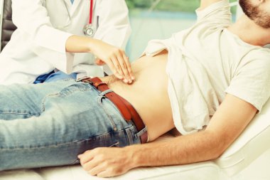 Kadın doktor konuşuyor ve erkek hasta hastane ofisinde inceleyerek. Sağlık ve tıbbi hizmet.