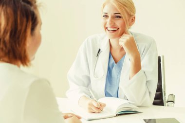 Kadın doktor konuşuyor ve Bayan hasta hastane ofisinde inceleyerek. Sağlık ve tıbbi hizmet.