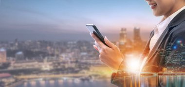 Cep telefonu ile modern şehir binaları arka plan kullanarak genç iş kadını. Gelecekteki telekomünikasyon teknolojisi ve internet şeyler (çok) kavramının.