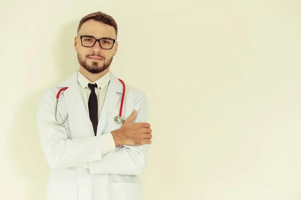 Joven Médico Guapo Con Los Brazos Cruzados Pie Sobre Fondo — Foto de Stock