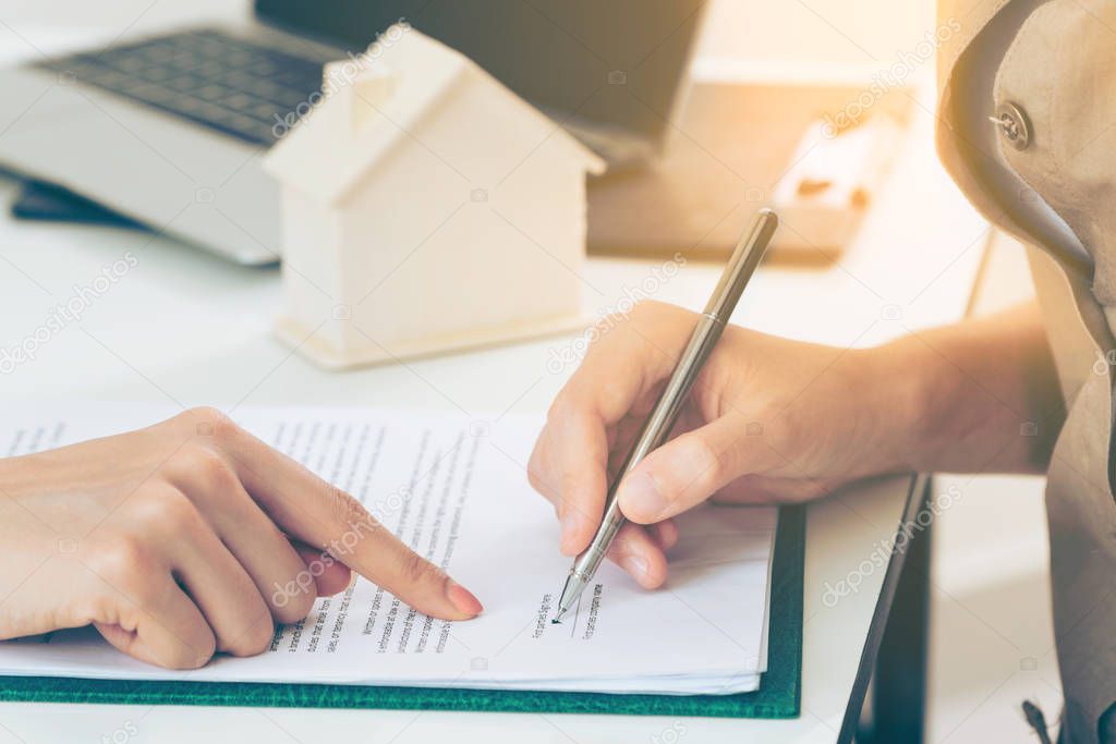 Client signs document regarding real estate activity. Lawyer or real estate agent points at the signature point. Business concept of selling and buying house.