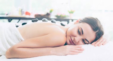 Kadın kaplıca salonunda profesyonel güzellik terapisti tarafından sıcak taş masajı görüyor. Lüks sağlık, sırt stresi ve gençleştirme kavramı..