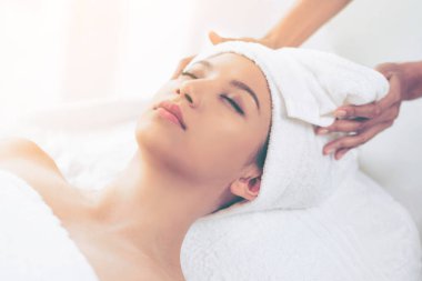 Spa yatağında uzanan rahat genç bir kadın lüks bir spa merkezinde yüz bakımı ve masaj için hazırlandı. Sağlık, stres atma ve gençleştirme kavramı.