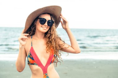 Tatil seyahat etmek tatil için yaz aylarında tropikal plaj keyfi yerinde mayo giyen mutlu genç kadın.
